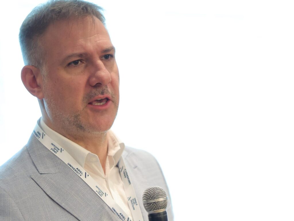 Michał P. Dybowski podczas wystąpienia z mikrofonem, Ariel University